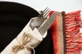 Vintage old fork and knife wrapped in a napkin lie on a black plate on a white background, word serving Royalty Free Stock Photo