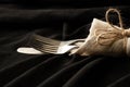 Vintage old fork and knife wrapped in a napkin lie on a black tablecloth on the table, word serving Royalty Free Stock Photo