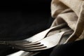 Vintage old fork and knife wrapped in a napkin lie on a black tablecloth on the table, word serving Royalty Free Stock Photo
