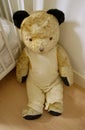 Vintage old large stuffed teddy bear sitting on the floor