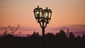 Vintage old lit lightpost at the dusk. Sunset sky on the background