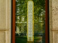 Vintage old thermometer behind glass window reflecting green park and trees