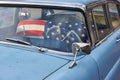 Vintage old timer car with hood ornament and american flag covering the front seat