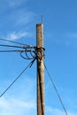 Vintage old wooden utility pole with multiple electrical wires connected with rusted holders going in all directions