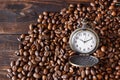 Vintage opened pocket watch among coffee beans on brown wooden table. Morning coffee,10 o`clock. Royalty Free Stock Photo