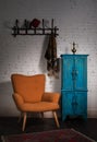 Vintage orange armchair, blue cupboard, wall hanger and black scarf