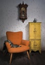 Vintage orange armchair, yellow cupboard, pendulum clock and black scarf
