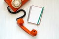 Vintage orange telephone and blank notebook Royalty Free Stock Photo