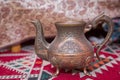 Vintage oriental teapot on a background of carpet .Beautiful vintage copper teapot kettle with tarnished metal, sitting background