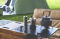 Vintage black kettle and coffee grinder on camping table with brown armchair on green lawn in camping area Royalty Free Stock Photo