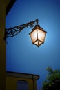 Illuminated old iron lantern on the wall at night. Royalty Free Stock Photo