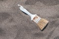 Vintage painting brush on sand. Artist`s brush on beach sand top view with copy space. Decaying painter`s brush close-up.