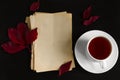 vintage paper sheets,red autumn leaves and hot tea cup flat lay on a black background Royalty Free Stock Photo