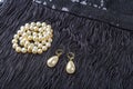 Vintage pearl jewelry on little black dress. Gatsby or Chicago fashion look. Luxury white necklace and earrings. Getting ready for