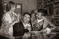 Vintage trio of people in period costume sitting around piano playing tunes and singing songs, laughing and smiling