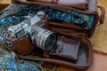 A vintage photo camera and a brown leather bag with scarf on sack cloth background Royalty Free Stock Photo