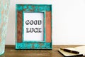 Vintage photo frame on wooden table with text GOOD LUCK