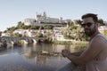 Vintage photo of a man with sunglasses in front of the view of a gothic cathedral on top of a hill in a city