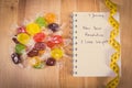 Vintage photo, New years resolutions written in notebook, candies and tape measure Royalty Free Stock Photo