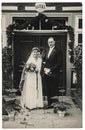 Vintage photo of newlyweds. Bride wears white clothes. Groom wears posh clothing white bow-tie. Outsides photo. Newlyweds in