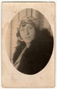 Vintage photo shows an elegant woman wears fur scarf. Antique black white photo is oval shaped.