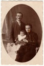 Vintage photo shows family - father, mother and baby boy. Retro black and white studio photography of a bourgeois family