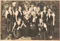 The vintage photo shows a group of people celebrating social event. Carnival masquerade ball dancing party
