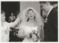 Vintage photo shows smiling bride with bridegroom. Happy bride wears a soft veil and holds wedding flowers - bouquet