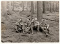 Vintage photo shows soldiers pose with beer bottles outdoors. Black and white antique photo.