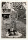 Vintage photo shows soldiers pose in front of barracks. Black and white antique photo.