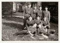 Vintage photo shows soldiers pose in front of barracks. Black and white antique photo.