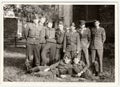 Vintage photo shows soldiers pose in front of barracks. Black and white antique photo.