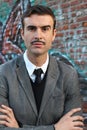 Vintage photo of a young elegant classic man with his arms crossed in modern graffiti background