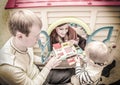 Vintage photo of young family playing with toy cash register in Royalty Free Stock Photo