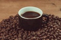 Vintage photograph of a cup of black espresso, accompanied by coffee beans on a wooden table. Royalty Free Stock Photo