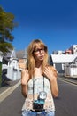 Vintage photography in a vintage neighbourhood. A stylish young girl with a vintage camera standing in a road in a quiet