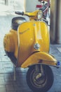 Vintage Piaggio Vespa in yellow color parked in the street