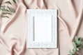 Vintage picture frame mockup and eucalyptus leaves on silk. Flat lay, top view, copy space. Mothers` Day greeting card template Royalty Free Stock Photo