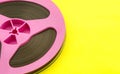 Vintage pink audio reel with recording tape on yellow paper background. Trendy pop art style. Royalty Free Stock Photo