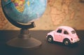 Vintage pink car and globe on a map background, close-up Royalty Free Stock Photo