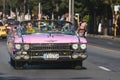 Vintage pink car on a street in a quaint city at daytime