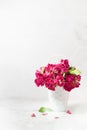 Vintage pink dry tiny roses in white wicker basket in airy soft light white interior with sunbeams, copy space, vertical. Holiday.