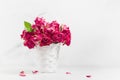 Vintage pink dry tiny roses in white wicker basket in airy soft light white interior with sunbeams, copy space. Holiday floral.