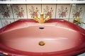 Vintage pink sink with gold faucet and flower pattern tiled wall in bathroom Royalty Free Stock Photo