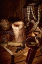 Pirate still life with candle, compass, dark rum in a skull bottle and old papers