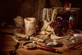 Pirate still life with candle, compass, dark rum in a skull bottle and old papers