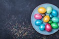 Vintage plate with colorful eggs on black table top view. Easter background.