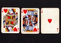 Vintage playing cards showing a run of queen, king and ace of hearts on a black background. Royalty Free Stock Photo