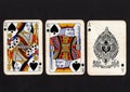 Vintage playing cards showing a run of queen, king and ace of spades on a black background. Royalty Free Stock Photo
