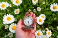 Vintage Pocket Watch in Hand against a Daisy Field Backdrop